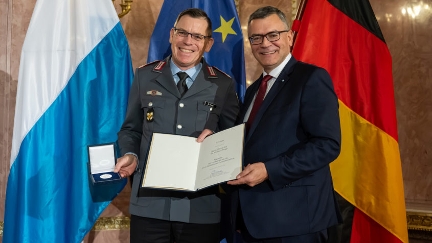 Staatsminister Dr. Florian Herrmann verleiht die Medaille für Verdienste um die Zivil-Militärische Zusammenarbeit unter anderem an Oberst d.R. Dr. Gerhard Tropp.