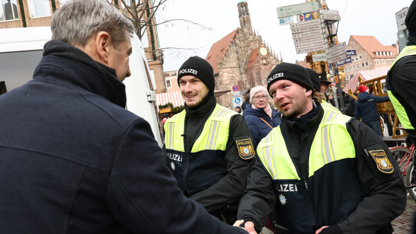 Ministerpräsident Dr. Markus Söder im Gespräch mit Polizisten auf dem Nürnberger Christkindlesmarkt.