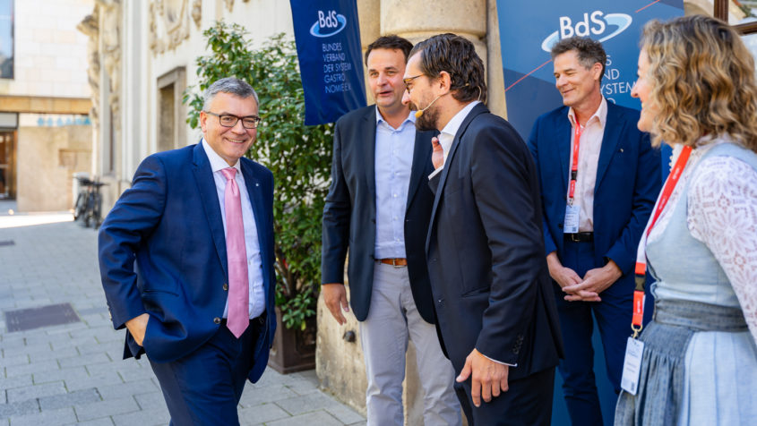 Mittagsempfang des Bundesverbands Systemgastronomie (BdS) im Münchner Künstlerhaus: Staatsminister Dr. Florian Herrmann (links) wird von BdS-Präsident Matthias Kutzer (2. von links) sowie BdS-Hauptgeschäftsführer Markus Suchert (Mitte) begrüßt. © BdS / Nadine Ingold