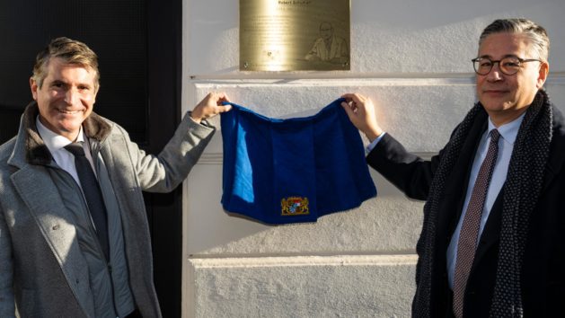 Europaminister Eric Beißwenger (links) und der französische Generalkonsul Alexandre Vulic (rechts) enthüllen eine Schuman-Plakette am Gebäude der Schraudolphstraße 44 in München.